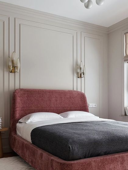Simple yet elegant is always a great theme. This bedroom features a soft pink upholstered bed with a curved headboard, set against a wall with classic moulding for a timeless and sophisticated look.