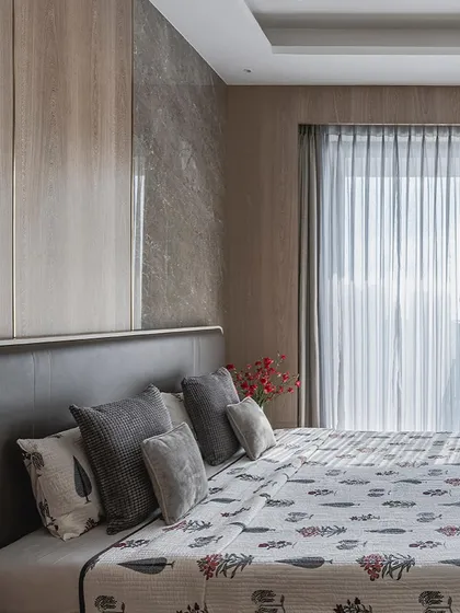 A serene bedroom where soft greys, warm beiges, and cool whites come together. The patterned quilt adds a touch of Indian motif to the contemporary space.