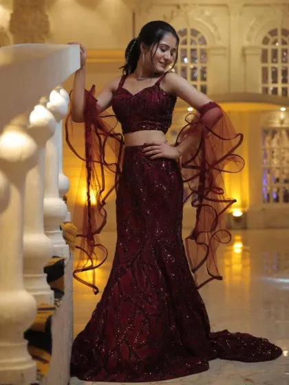 A modern and chic choice, this maroon sequined mermaid skirt is paired with a matching crop top and dramatic ruffled sleeves.