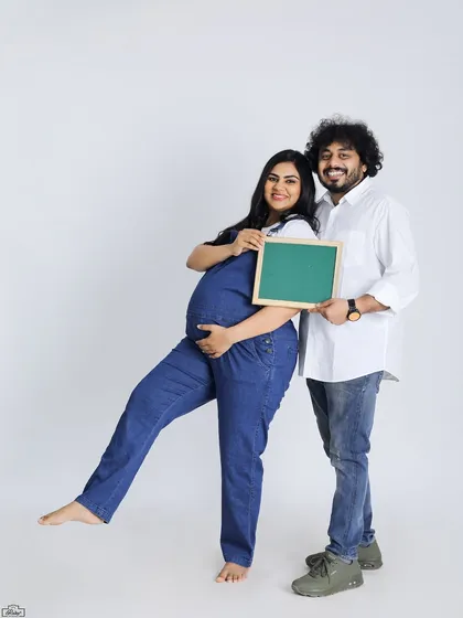 A fun and classic studio portrait of an expecting couple. They hold a blank chalkboard, perfect for adding a personalized message or due date announcement.