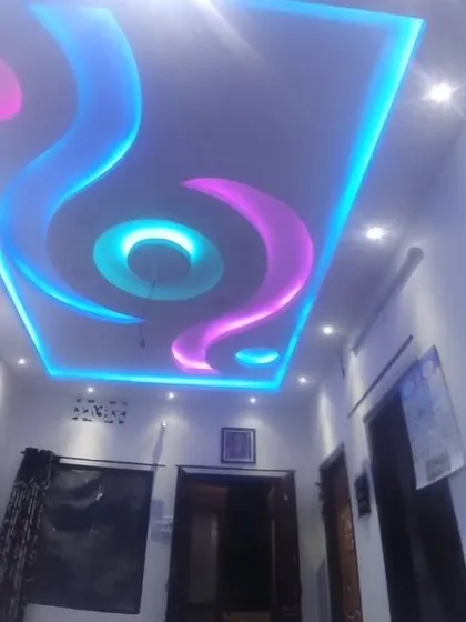 This video shows a living room with a flowing, wave-like ceiling design. The alternating blue and pink lights create a party-like atmosphere.