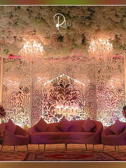 A lounge area with a backdrop of intricate white jaali panels and a ceiling covered in baby's breath, creating a light and ethereal feel.