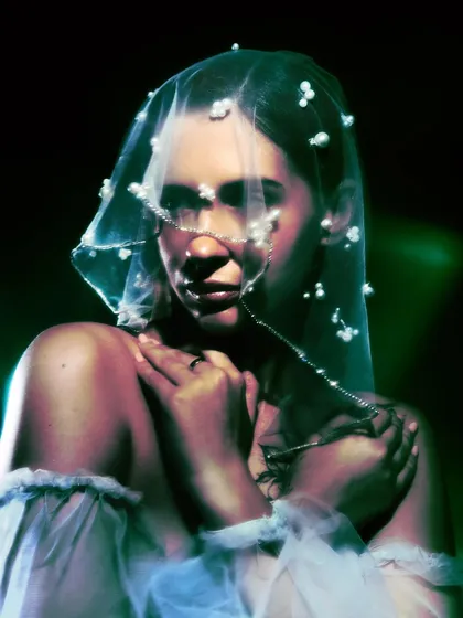 A close-up from 'Whispering Veil,' focusing on the custom pearl headpiece. The green light and the model's expression create an intimate and slightly haunting mood.