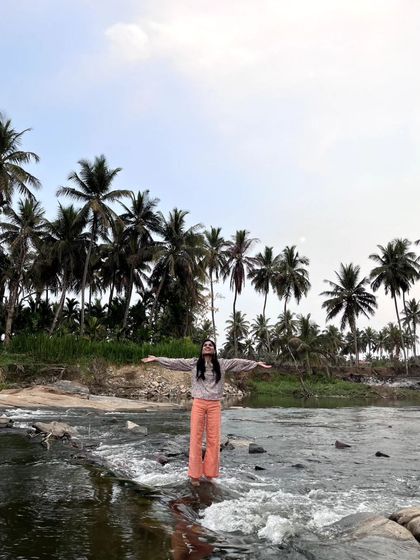Arms outstretched, embracing the beauty of the river and the palm trees. A moment of pure gratitude for the natural world.