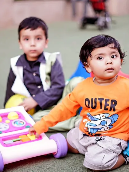 Two young boys playing with toys outdoors, a candid shot that captures natural interaction between children.