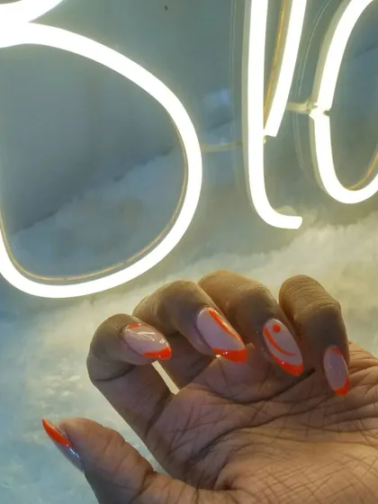 A close-up of the neon orange abstract nails against our studio's neon sign. So cool.