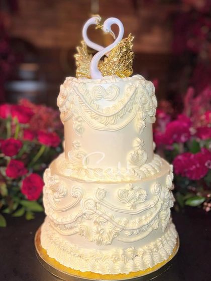 A grand, two-tiered vintage-style cake for a 25th anniversary. The intricate, old-school piping work and the elegant swan topper make it a timeless centerpiece for a milestone celebration.