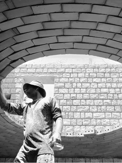 Brick by brick, an earthen shell structure is formed. This image captures a mason at work on the Rohtak Dome, showcasing the raw beauty of the construction phase.