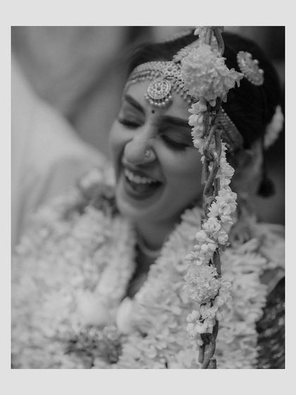 A black and white photo capturing the pure, uninhibited laughter of a bride. This candid moment is a beautiful testament to the joy of a wedding day.