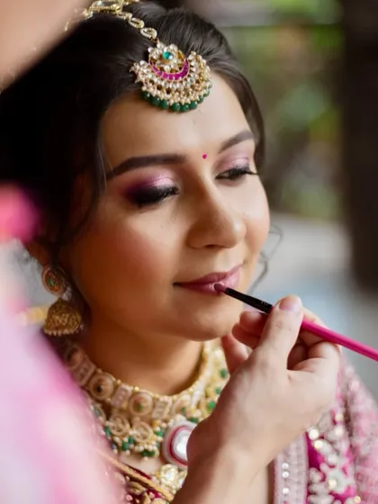 A behind-the-scenes moment of applying the final touches. This shot shows the detail that goes into creating the perfect bridal lip to complement the soft pink eyeshadow and flushed cheeks.