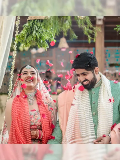 Pure joy captured in a shower of rose petals. This candid moment of the bride and groom laughing together is what makes wedding photography so special.