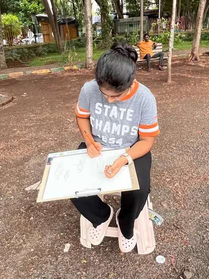 Another student deeply focused on her clipboard, sketching the scenes around her. Outdoor drawing is a practical application of the anatomy and perspective lessons learned in the studio.