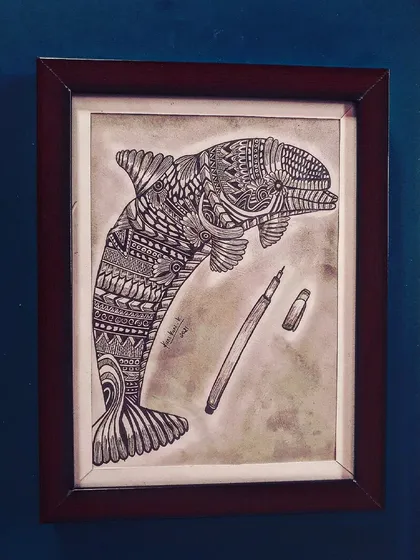 A zentangle dolphin drawing, with a pen included in the frame to show the tool of creation.