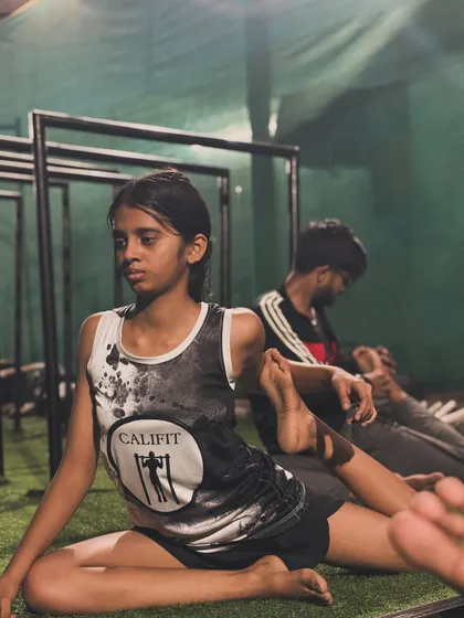 A young athlete holds a deep pigeon pose during our mobility class. This stretch is excellent for releasing tight hips, which is crucial for calisthenics.