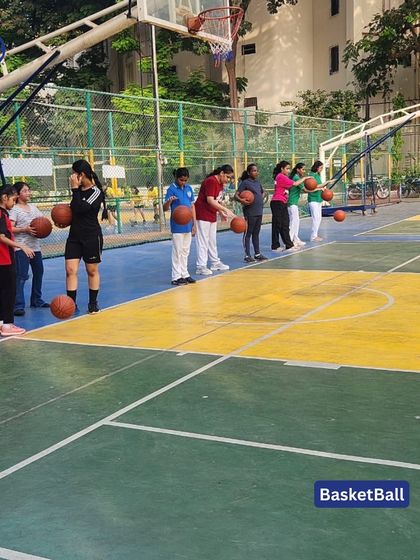 A group of girls lines up to practice their basketball shooting. We provide dedicated coaching for all students, ensuring everyone gets a chance to learn and play.