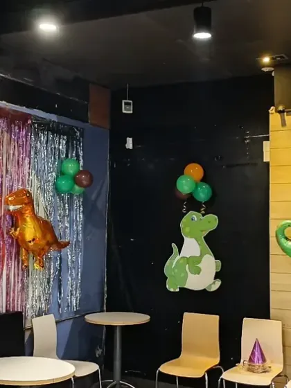 A corner of the party area decorated with a tinsel wall and dinosaur foil balloons, creating a fun photo spot.