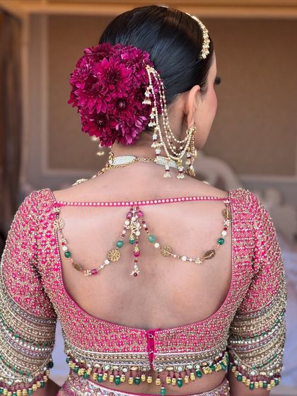 A side profile of the vibrant magenta floral bun, showing how it complements the bride's jewelry.