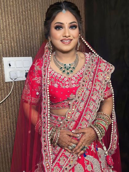 This bride looks absolutely radiant. I created a look with a dewy finish, smokey eyes, and a soft red lip to complement her red and green jewelry.