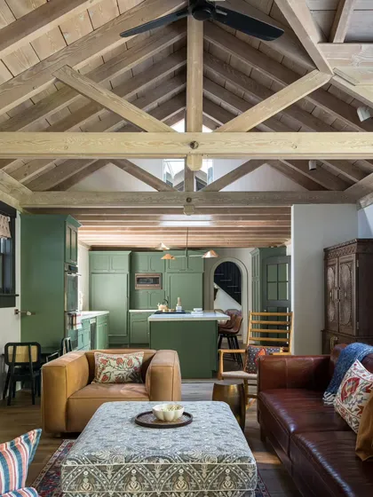 An open-concept design in this Saratoga home connects the kitchen and living areas. The olive green kitchen cabinetry provides a beautiful, earthy focal point, while the vaulted wood ceiling ties the entire space together with rustic warmth.