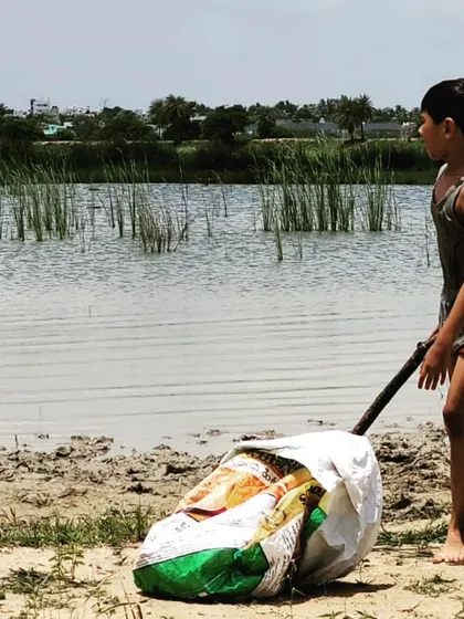 A child single-handedly transports a heavy bag of harvested clay. This moment shows incredible determination and the development of practical problem-solving skills, using a simple stick as a lever to move the load.