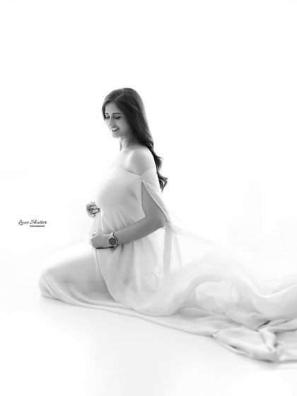 A joyful moment captured in classic black and white. The simple background ensures that her radiant smile and the beautiful shape of her baby bump are the stars of the show.