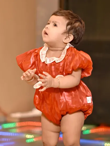 An outfit change for the birthday girl! This candid shot captures her looking up with wonder, a perfect memory from her first birthday event photography session.