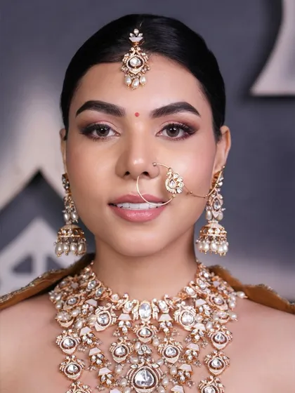 A close-up of a sleek and clean bridal updo, showing how it perfectly frames the face and allows the statement jewelry, like the maang tikka and nath, to shine.