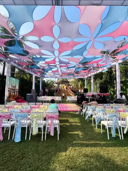 The seating area for the 'Mumbai Fiesta' Haldi, with a colorful floral-patterned canopy and bright chair ties.
