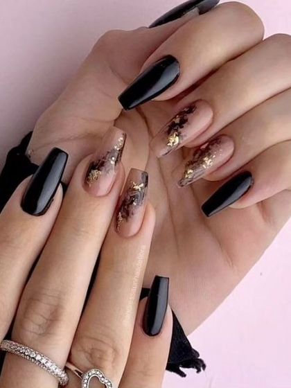 A chic and sophisticated black marble design. This look combines solid glossy black nails with accent nails featuring a black smoke effect and gold foil on a nude base.