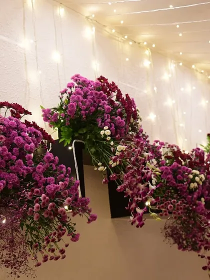 A cascading floral arrangement designed to sit atop a console or mantelpiece. The varying lengths and shades of purple create a sense of movement and drama.