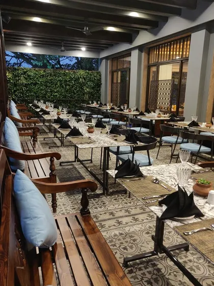 The outdoor seating area for Ebony Restaurant, featuring patterned tile flooring and a lush green wall. We designed this space to offer an alfresco dining experience that feels both elegant and connected to nature.