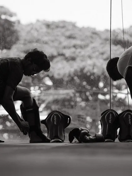 The silhouette of two fighters preparing their gear against the bright window.