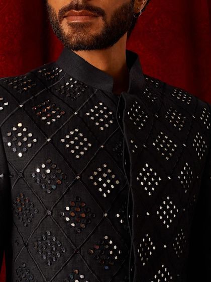 A close-up of our black bandi jacket with geometric mirror work. The play of light on the mirrors against the dark fabric creates a dynamic and eye-catching effect.