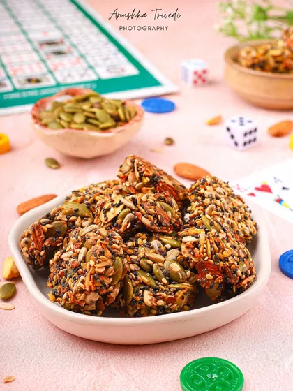 A bowl of healthy, multi-seed bites styled with game pieces. This playful concept connects the idea of a fun game night with a healthy snack option.