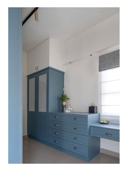 The spacious walk-in wardrobe and dressing area in the master bedroom, finished in a calming blue. The design includes a mix of open and closed storage and a dedicated vanity.