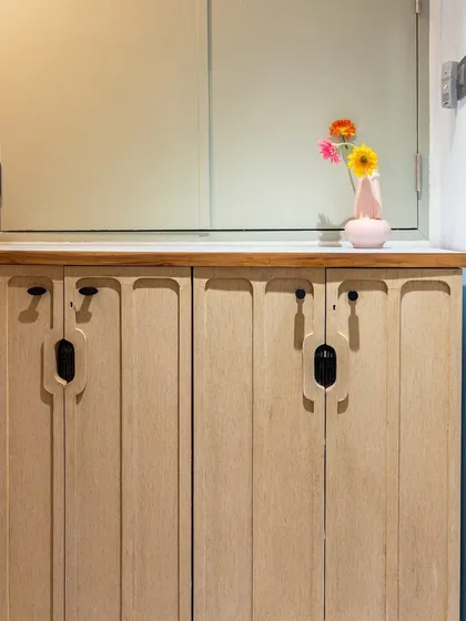 A detail shot of the custom shoe storage cabinet, featuring unique grooved handles that add an organic and modern touch to the entryway.