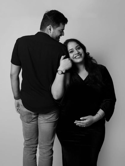 The pure joy of pregnancy shines in this black and white photo. The mother-to-be leans on her partner with a happy smile, a simple and beautiful moment.