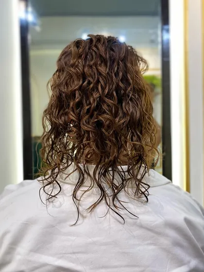 This is the client's hair before we began styling the updo. Her hair has a lovely natural wave and curl pattern, providing the perfect foundation for creating a textured, romantic hairstyle.