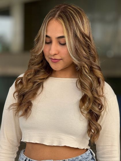 Here is another fantastic makeover by a student. This style features prominent face framing highlights, also known as a money piece, combined with soft waves for a trendy and glamorous result.