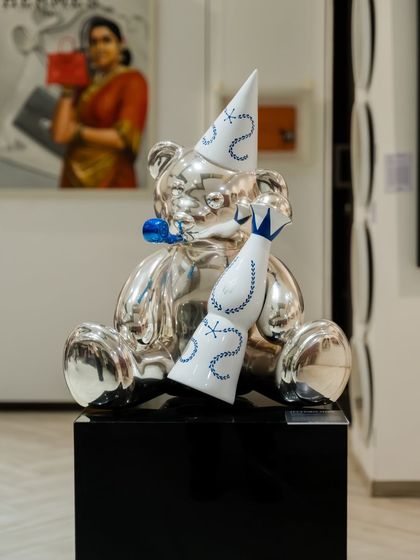 A silver chrome version of the "Let's Party Teddy," reflecting its surroundings and capturing a moment of playful indulgence. The stylized bottle and party hat complete this tribute to youthful exuberance.