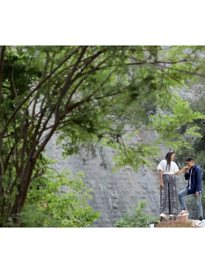 A chivalrous moment captured in a natural setting, with the groom kissing the bride's hand.