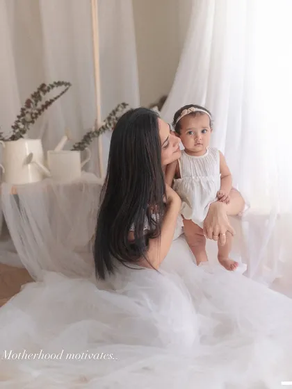 A quiet moment of connection. The mother leans in close to her baby, a simple gesture that speaks volumes about their bond. The soft, dreamy light enhances the intimacy.