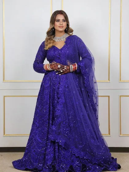 A full-length shot of the bride in her blue lehenga, where the dark, beautiful stain of her mehndi is clearly visible, adding to her overall grace.