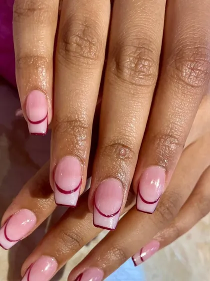 A minimalist yet chic take on the French manicure, featuring a clean, sheer pink base with a fine, deep red line tracing the cuticle for a unique, reversed effect.