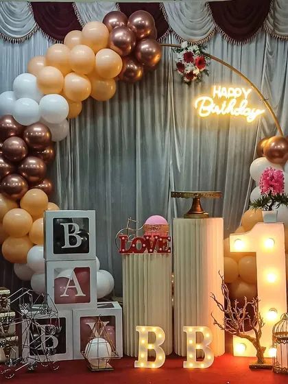 Celebrating a first birthday with a beautiful rose gold and white balloon arch. This setup includes a large marquee number '1', 'BABY' blocks, and light-up 'BB' initials for a personalized and memorable photo opportunity.