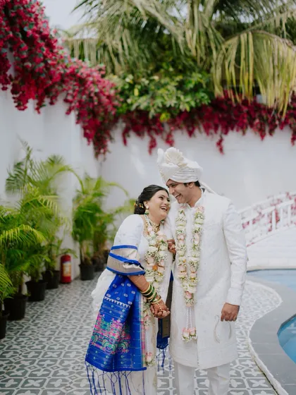 A happy, candid moment between a newly married couple in their traditional Maharashtrian wedding attire.