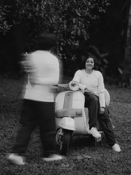 A creative black and white shot with motion blur, capturing the groom walking towards the bride on a scooter.