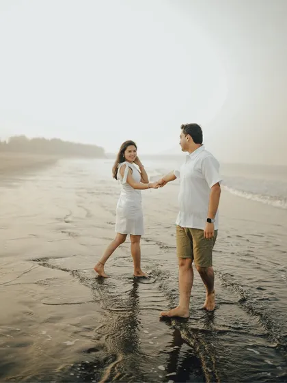 A gentle walk along the water's edge. This candid pre-wedding photograph captures a natural, comfortable moment between the couple during their beach session.