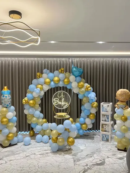 A beautiful "Oh Baby" setup for a home celebration. This full balloon ring in pastel blue, white, and gold creates a perfect photo corner, complete with balloon pillars and 'BABY' blocks.