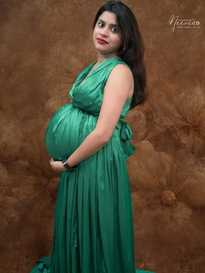 A simple and stunning portrait focusing on the baby bump. The rich green of the satin dress looks beautiful against the textured backdrop.